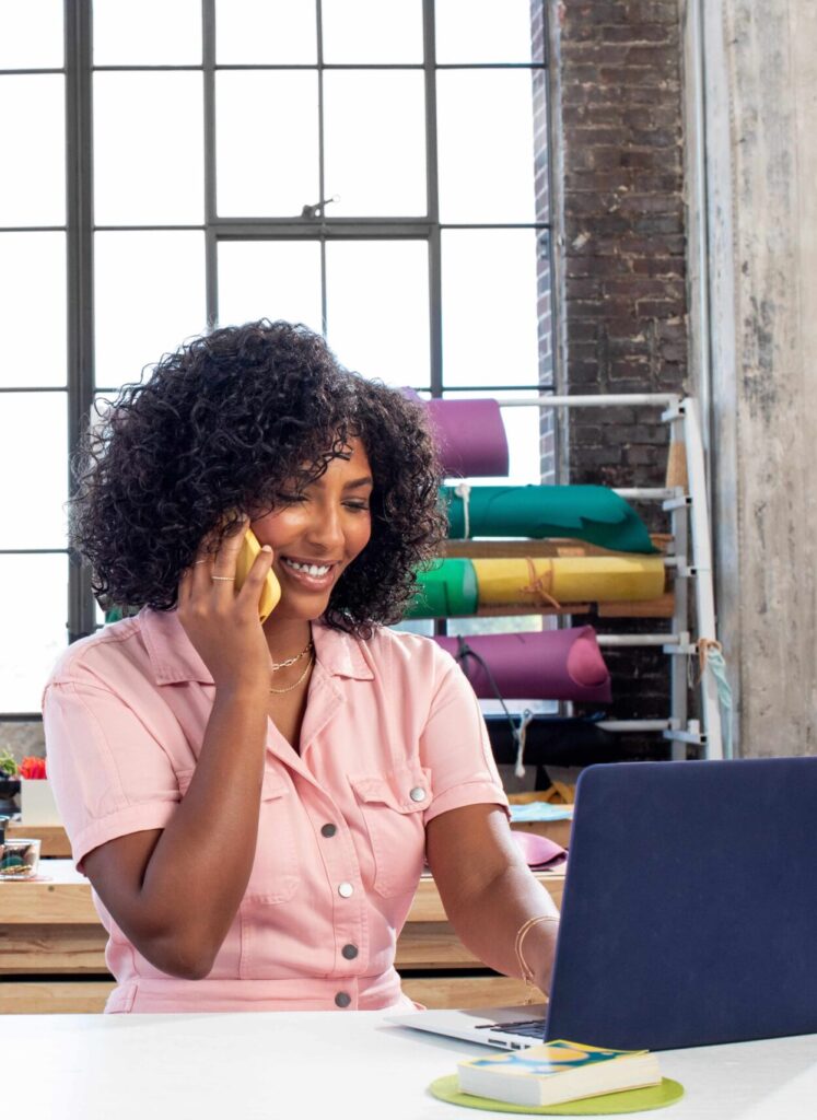 Marketing professional working on a laptop with analytics and campaign materials spread across the table.